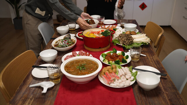 Cropped View Of Senior Host Of Family Grandfather Clapping Hands And Gesturing Members To Sit Down At Dining Table. People Pulling Out Chair, Starting To Eat Big Meal For Chinese New Year