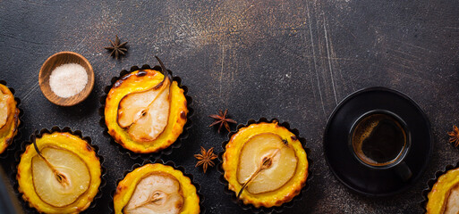 Pears and custard mini tarts on a dark brown concrete old table background. Top view.