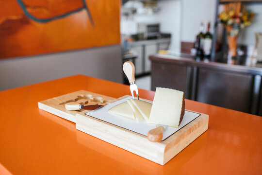 Manchego cheese with knives at counter