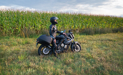 Obraz premium sense of adventure she and her motorcycle resting for a moment on the side of a rural road of sun-drenched agricultural fields in the golden hour
