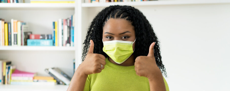 Young African American Woman With Green Face Mask Showing Both Thumbs Up