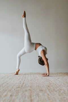 Flexible yogi practicing Eka Pada Urdhva Dhanurasana on carpet at health club