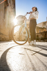 young woman on a bicycle on a sunny day explores the city in italy