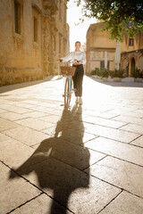 young girl walks pushing a bicycle on a sunny day in a city break