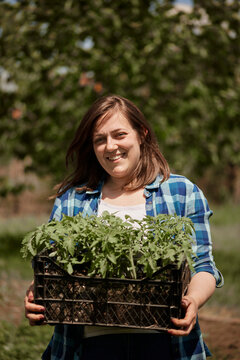 Smiling woman holding crate of seedlings in back yard