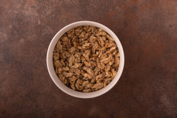 Shredded walnut in a light small bowl on a vintage rusty background. The concept of the beneficial...