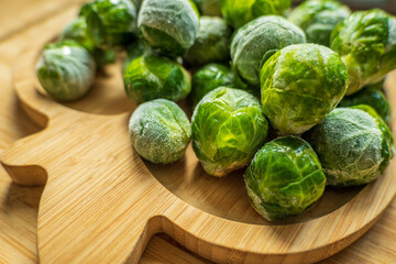 frozen frosty brussels sprouts on wooden plate closeup