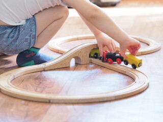 child plays in the children's wooden railroad in home room