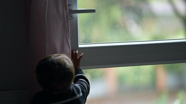 Child closing window. Toddler closes window
