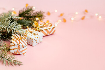 White gift boxes with golden bow with snowy fir branches on pastel pink background. Christmas, new year, festive, holiday, celebration or winter background with copy space. Online shopping and sale.
