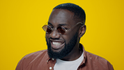 Obraz premium Portrait of smiling african american man dancing on yellow background.