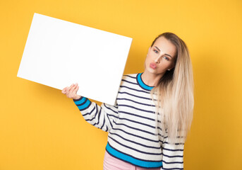 Obraz na płótnie Canvas Young women holding white speech bubble, isolated on yellow background. Promoter girl showing blank empty white board with space for suggestion or opinion