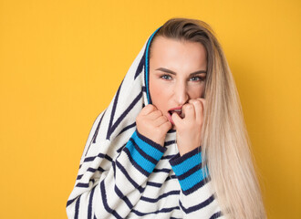 Panicked young woman biting fingernail, being terrible accident, isolated on yellow background