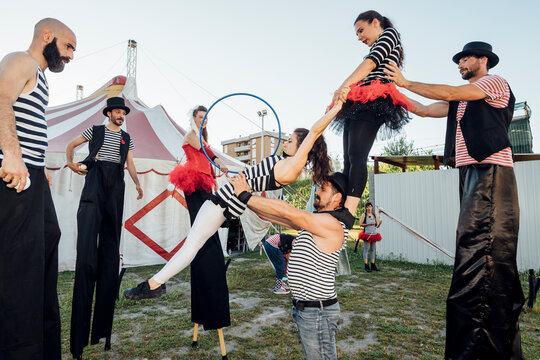 Circus acrobats and artist practicing with each other behind circus tent