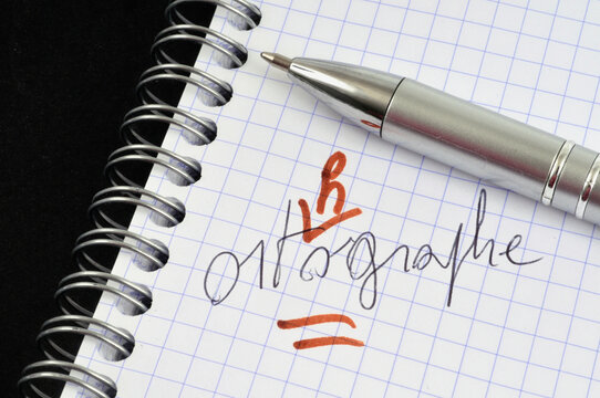 Le mot orthographe &eacute;crit et corrig&eacute; sur un cahier &agrave; spirales avec un stylo en gros plan