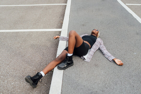 Carefree woman with arms outstretched lying on road in city