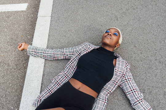 Woman with arms outstretched resting while lying on road