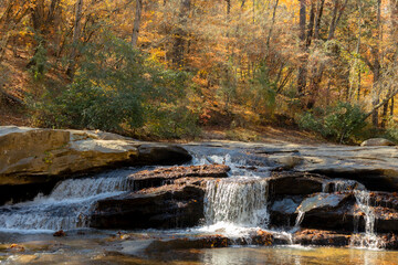 A small waterfall over rocks in the autumn woods.