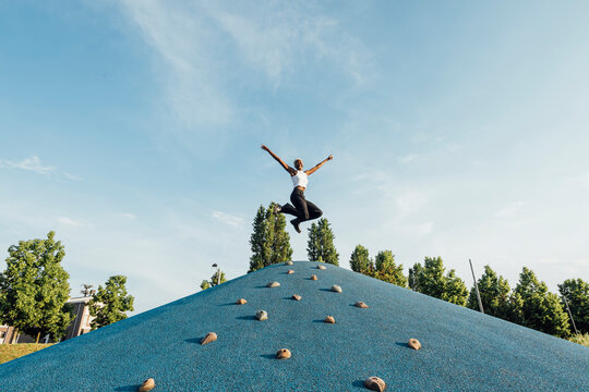 Woman with arms outstretched jumping on climbing wall
