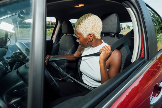 Woman fastening seat belt while sitting in car