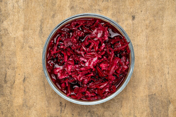 bowl of organic, red beets and cabbage sauerkraut against textured paper, probiotics concept -...