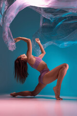 One young flexible contemp dancer dancing with fabric isolated on gradient blue white background in neon light