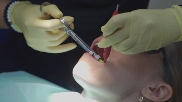 real. dentist injects an anesthetic into patient before tooth extraction