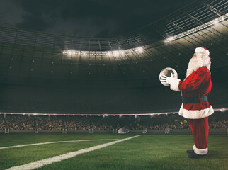 Santa Claus with a soccer ball in his hands inside a soccer stadium