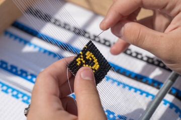 Young girl makes a beaded bracelet with her hands, Ukraine, close up