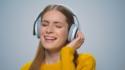 Closeup smiling woman listening music in headphones on grey background. 