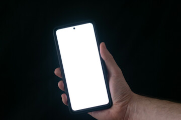 Human hand holding black smartphone with blank desktop screen. empty screen for mockup image for advertisement in black background