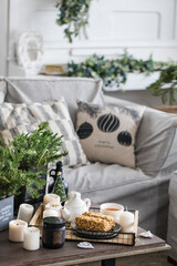Cake with nuts on a plate on a tray with a tea set and candles on the background of the sofa