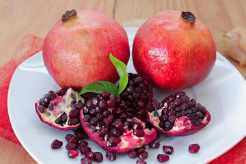 Two juicy pomegranates on white plate.