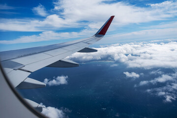 Classic image through aircraft window onto wing. Flight view over sea in cloudy weather