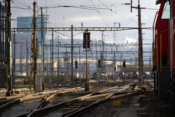 Naklejka premium Track field with railway switch and red shunting train at Zürich Altstetten on a cloudy winter day. Photo taken December 7th, 2021, Zurich, Switzerland.