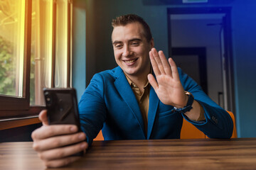 A young stylish guy, businessman of European appearance portrait sits at a table in a suit and...