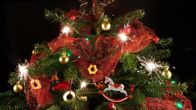 Kerze und Wunderkerzen am Weihnachtsbaum - Christbaum mit Zucker-Geb&auml;ck geschm&uuml;ckt