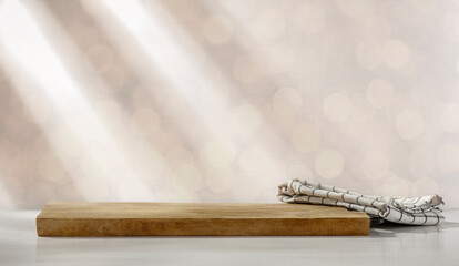 A wooden elevation on a white table and the background in blur with Christmas light rays 