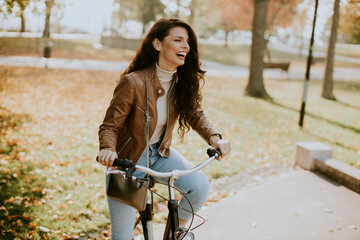 Fototapeta na wymiar Young woman riding bicycle on autumn day