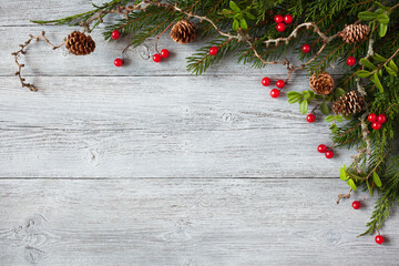Christmas wooden background with spruce branches, larch, thuja, cones, lingonberry leaves and red berries. Space for text and congratulations.