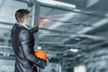 A man in a suit with a helmet in his hands works on a virtual screen with an industry project.