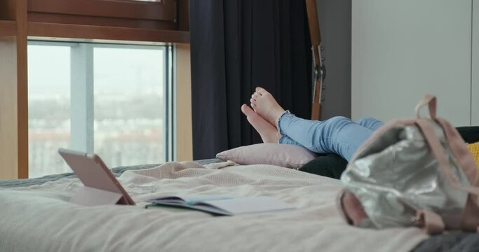 In The Frame Of The Legs Of A Girl Who Lies On The Bed And Relaxes On A Cloudy Day