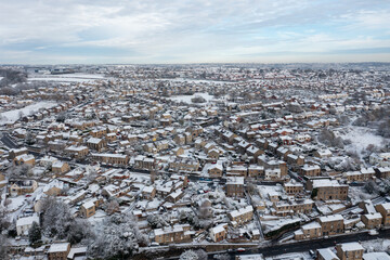 Aerial photo in the winter time on a snowy day of the British town of Mirfield in Kirklees, West Yorkshire, England showing residential housing estates and houses and homes with snow covered roofs