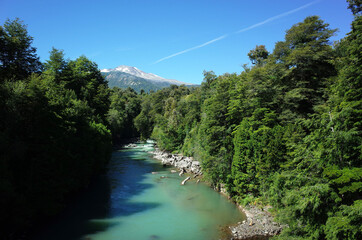 Turquoise water river in lush green forest with view of volcano Puyehue, Puyehue National Park, Los...
