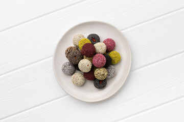 Colorful vegan candies energy balls on a plate on a white table.