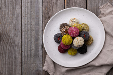 Raw energy bites balls prepared with natural ingredients on wooden background