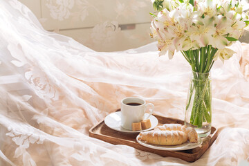 breakfast in bed with coffee, pastries and flowers on a tray. Romantic breakfast in bed.