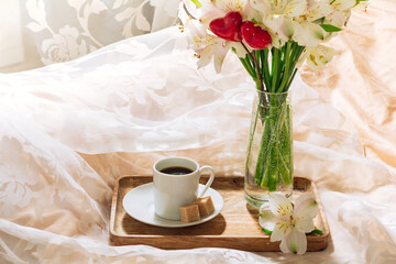 breakfast in bed with coffee and flowers on a tray. Romantic breakfast in bed.