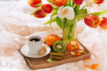 breakfast in bed with fruits, coffee and flowers on a tray. Romantic breakfast in bed