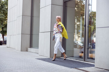 Young woman with laptop walking on city street